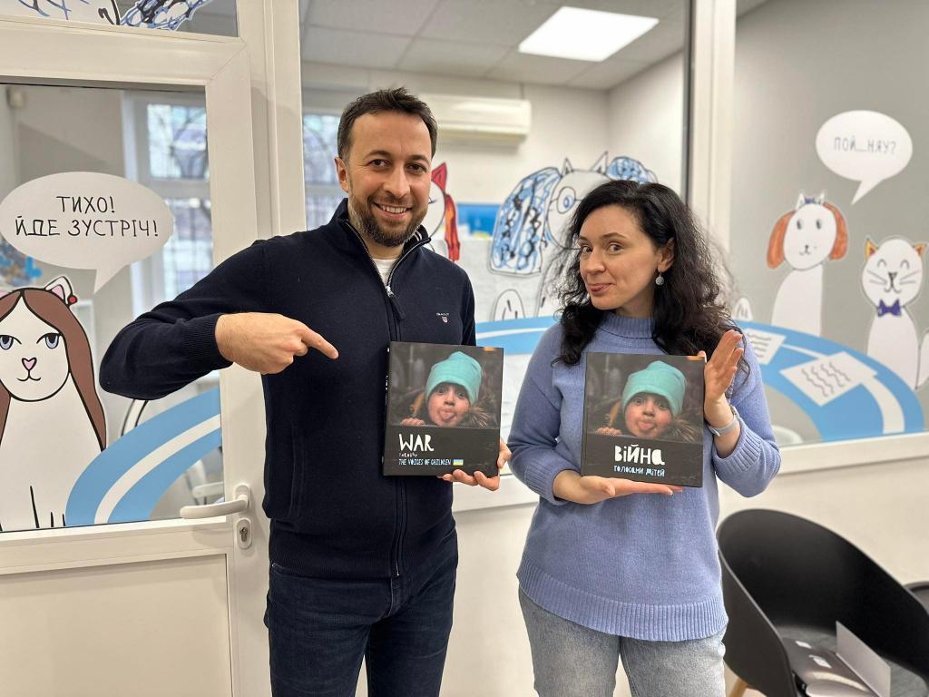 Режисер Азад Сафаров та Олена Розвадовська тримають у руках видану ними книгу «Війна голосами дітей»
